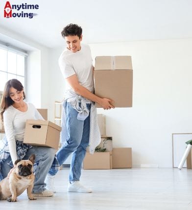 A couple carrying moving boxes in a new home, illustrating how much do movers cost for a local household move.